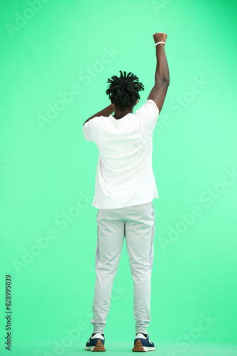 A man, full-length, on a green background, rejoices © Katsiaryna