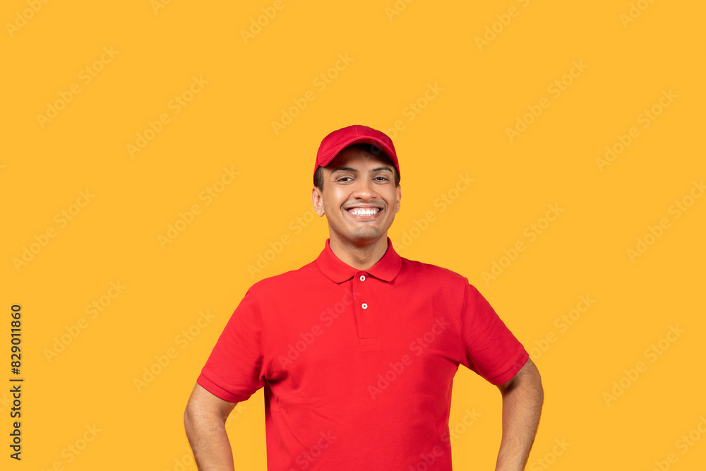 A cheerful man stands with his hands on his hips, wearing a bright red uniform and matching cap, against a vibrant yellow backdrop. He is smiling widely, appearing enthusiastic and approachable.