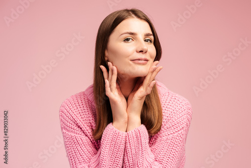 Portrait of attractive smiling woman looking in mirror standing isolated on pink background
