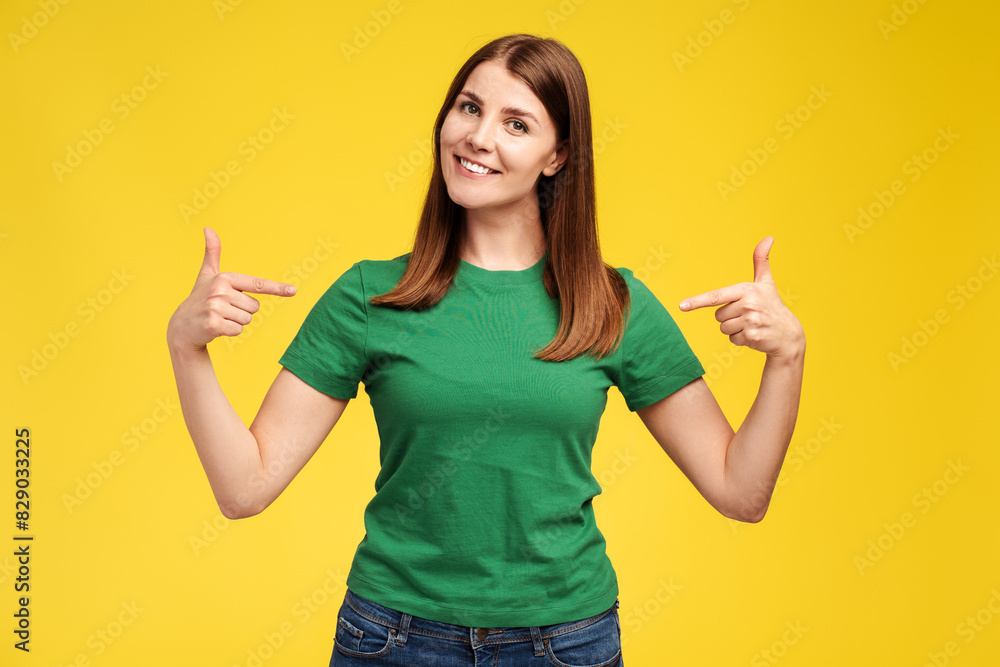 Smiling middle aged woman wearing stylish green t shirt pointing fingers at herself, mockup Smiling middle aged woman wearing stylish green t shirt pointing fingers at herself, mockup