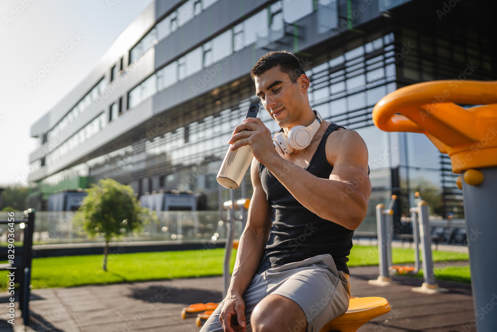 One caucasian man young male athlete take a brake during outdoor training in the park outdoor gym hold supplement shaker in hand happy confident strong copy space One caucasian man young male athlete take a brake during outdoor training in the park outdoor gym hold supplement shaker in hand happy confident strong copy space