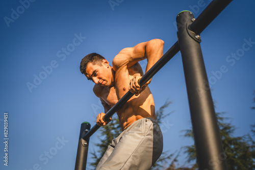 One man muscular male athlete training pull ups outdoor in sunny day © Miljan Živković
