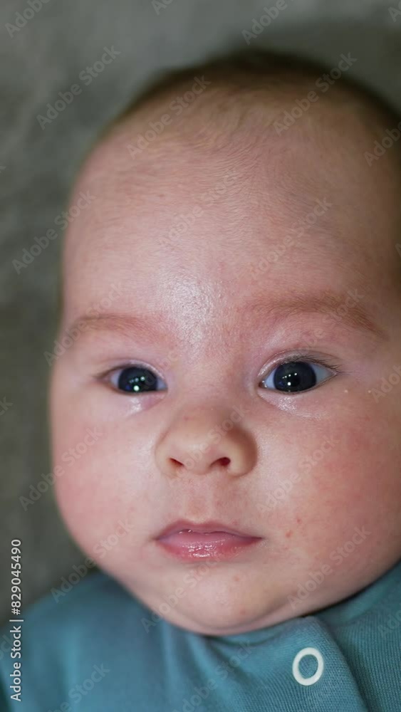 Little baby watching intensely into the camera. Cute child on the grey background. Close up. Vertical video Little baby watching intensely into the camera. Cute child on the grey background. Close up. Vertical video
