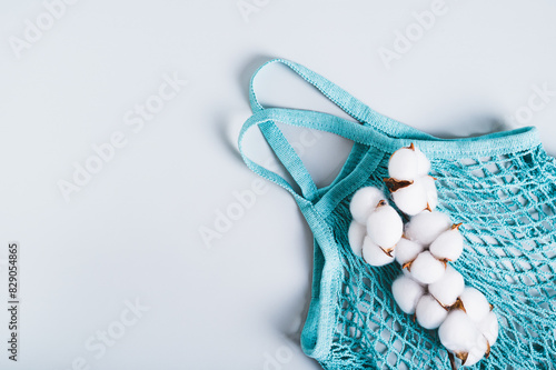 Concept of refusing plastic bags. String bag and cotton branch on a blue background