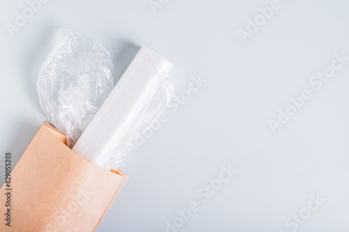 Roll of blank plastic bags in paper bag on blue background top view