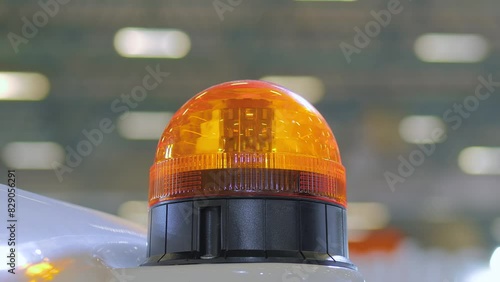 The warning orange beacon is flashing on the roof of emergency support and service vehicle against blurred background - close up shot. Alert light, danger, alertness, attention, and hazard concept photo