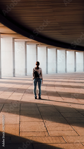 woman walks under gallery arcades in sun light