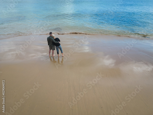 A young couple together on a beach in Portugal on a spring day, photo view from a drone.