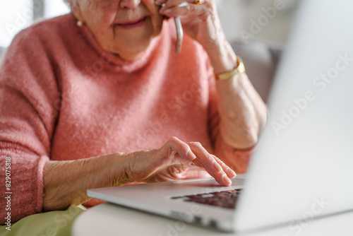 Online and phone scams targeting seniors. Scammer sending email to elderly woman, asking for money, demanding personal, sensitive informations without verification. photo