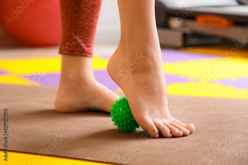 Sporty young woman massaging her foot with ball at gym  closeup