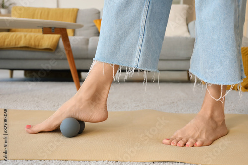 Mature woman massaging her foot with ball at home  closeup