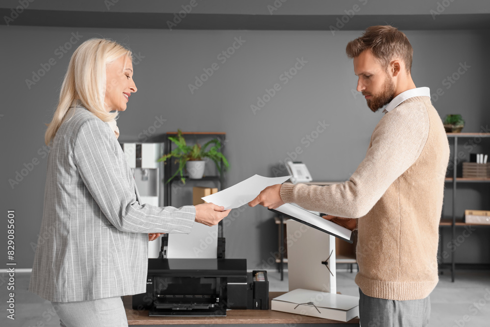 Fototapeta premium Mature businesswoman with her colleague printing document in office