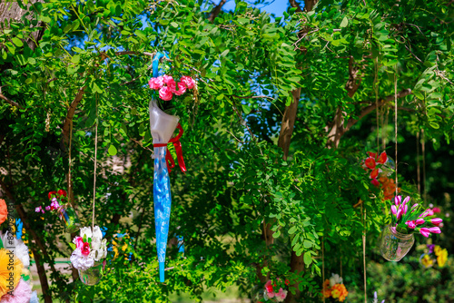 A tree with many flowers hanging from it, including a blue umbrella