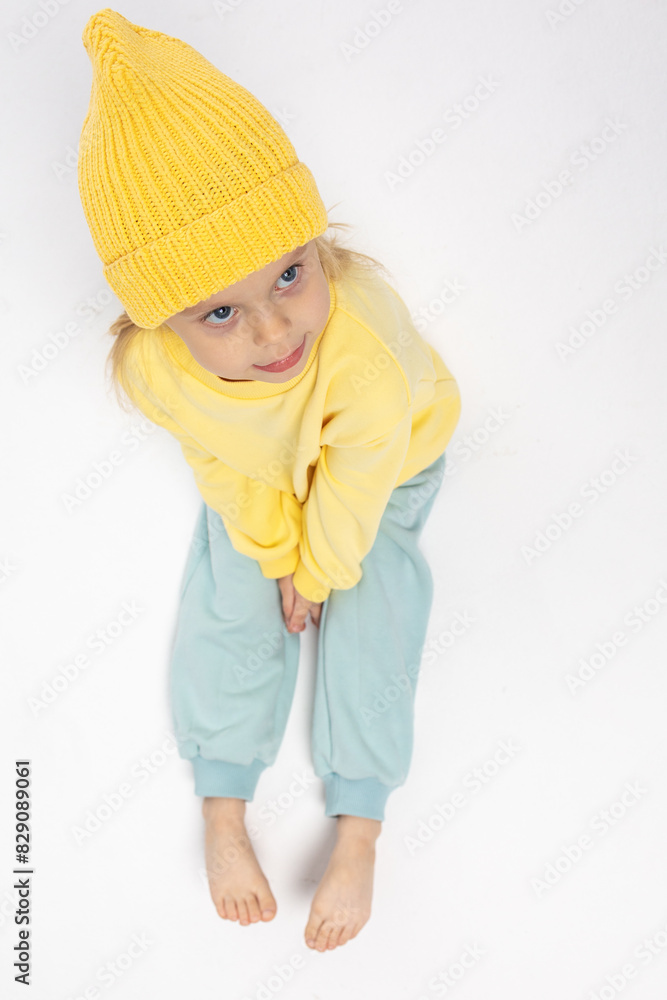Portrait of beautiful cute little toddler girl. Child with funny face in yellow sweatshirt and yellow hat. Pretty smile kid in studio on white background. High quality photo Portrait of beautiful cute little toddler girl. Child with funny face in yellow sweatshirt and yellow hat. Pretty smile kid in studio on white background. High quality photo