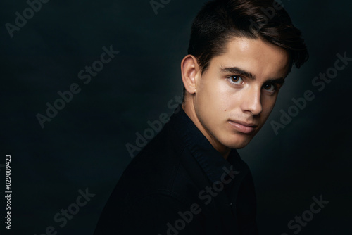 Portrait of a handsome young man in black in front of a black background photo