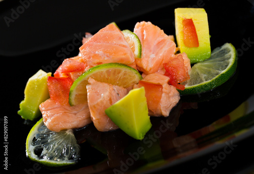 Black plate with delicious salmon ceviche with avocado and lime photo
