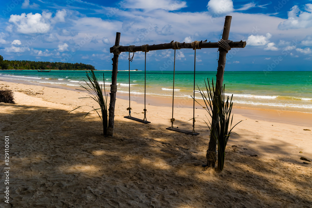 Wooden swings on a sandy tropical beach next to a warm ocean Wooden swings on a sandy tropical beach next to a warm ocean