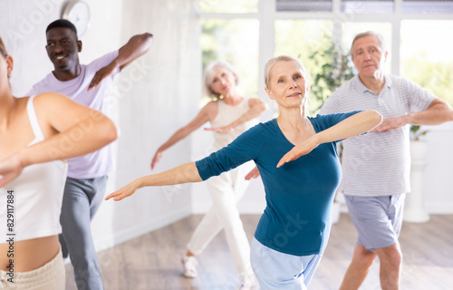 Group of multiethnic mature active people dancing classical dance movements in studio