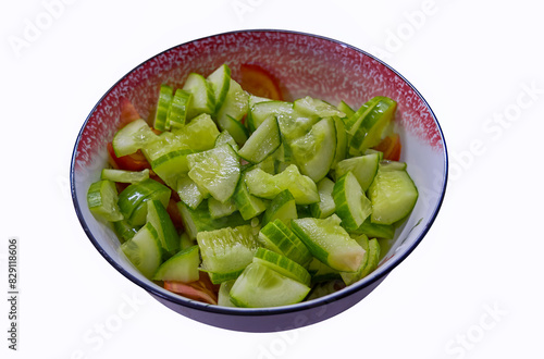 Vegetable salad of fresh cucumbers, tomatoes and herbs in a plate, isolate on a white background.