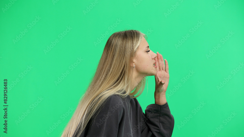 A woman, close-up, on a green background, tells a secret