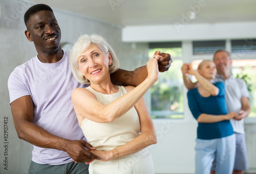 Group of positive adults doing Tango poses in training room during workout session