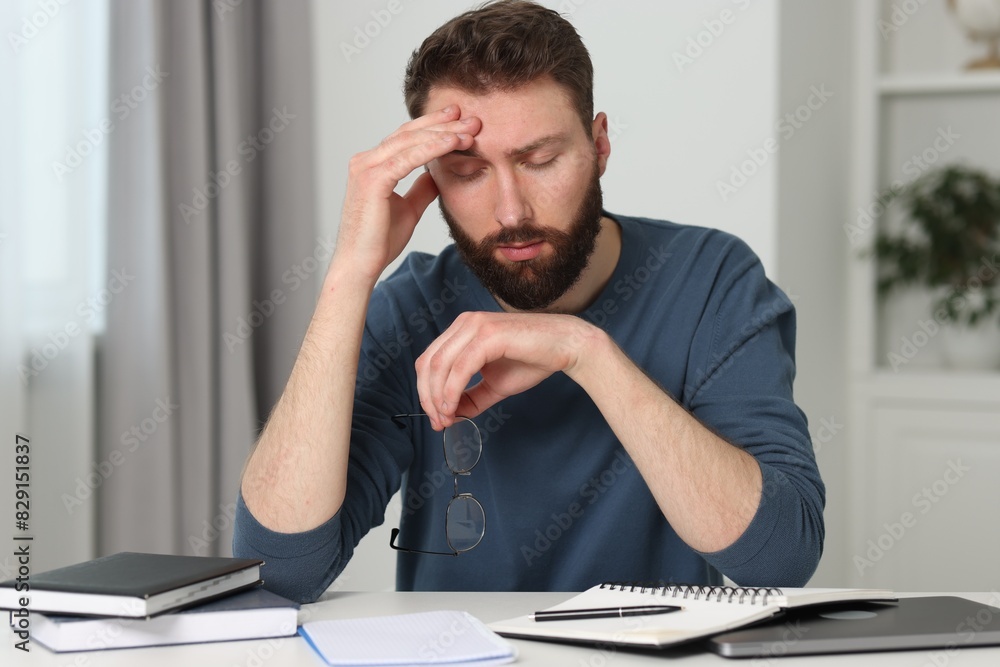 Overwhelmed man with glasses at table indoors Overwhelmed man with glasses at table indoors