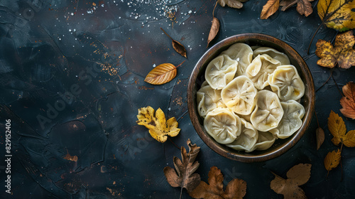 russian pelmeni dumplings in a rustic bowl with autumn leaves, top view with copy space photo