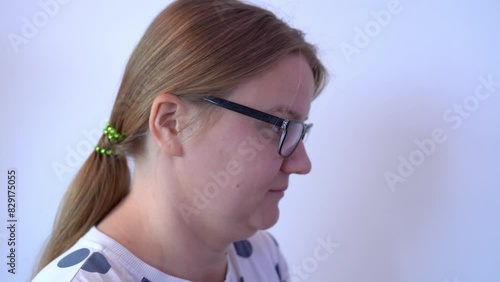 Portrait of woman with ponytail in glasses, looks critically with wrinkled forehead, rubbing temple with finger gesture, shows mentally retarded gesture, devaluation of child Abusive mother, teacher photo
