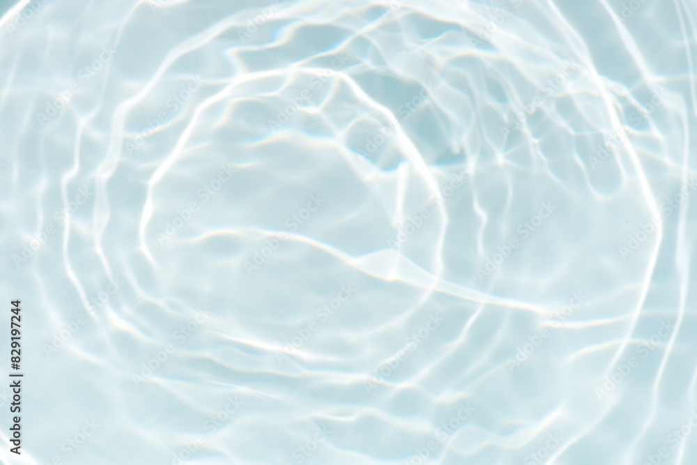 Obraz premium Blue water with ripples on the surface. Defocus blurred transparent blue colored clear calm water surface texture with splashes and bubbles. Water waves with shining pattern texture background.