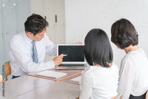 教室で三者面談をする担任の先生と親子（進路相談）
 photo