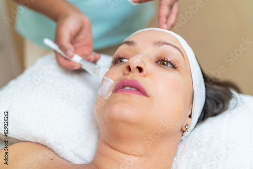 Dermatologist applying facial cream for peeling to a woman