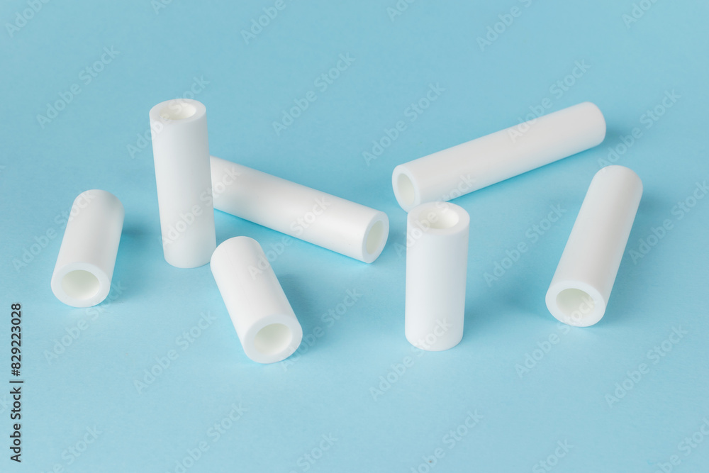 Obraz premium White Ceramic Tubes on Light Blue Background - Minimalist Industrial Elements
