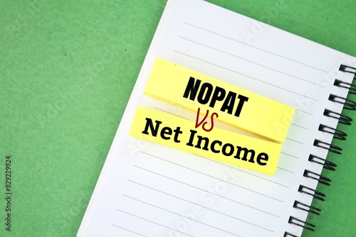 colored paper with the words nopat vs net income. financial performance metric that calculates profit gained through core operations after taxes. photo