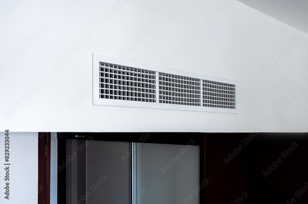 Side view of air conditioning wall mounted ventilation system on ceiling in the black and white hotel room. Hotel room air ventilation grill on the wall. Side view of air conditioning wall mounted ventilation system on ceiling in the black and white hotel room. Hotel room air ventilation grill on the wall.