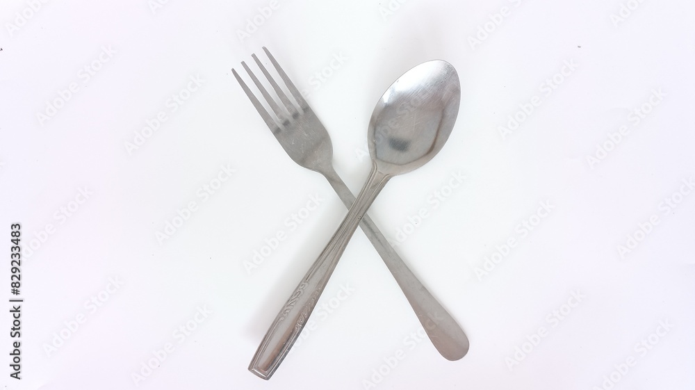 crossed spoon and fork made of stainless steel on a white background crossed spoon and fork made of stainless steel on a white background
