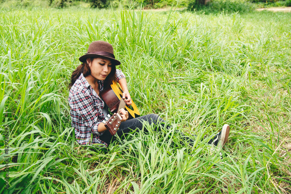 Young women playing acoustic guitar outdoor in green park. Woman person playing acoustic guitar music instrument at home, young Asian musician girl lifestyle in beautiful nature. Happy guitarist Young women playing acoustic guitar outdoor in green park. Woman person playing acoustic guitar music instrument at home, young Asian musician girl lifestyle in beautiful nature. Happy guitarist