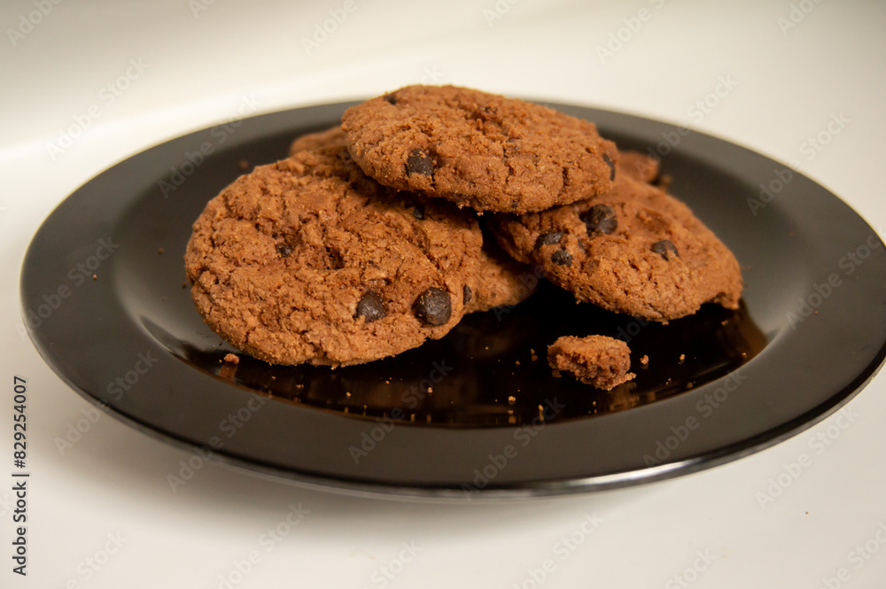 sweet chocolate biscuits on a black plate on a white background sweet chocolate biscuits on a black plate on a white background