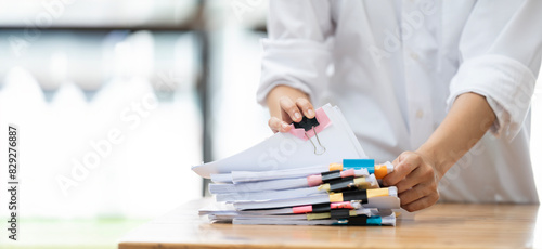 Businesswoman hands working in Stacks of paper files for searching and checking unfinished document achieves on folders papers.