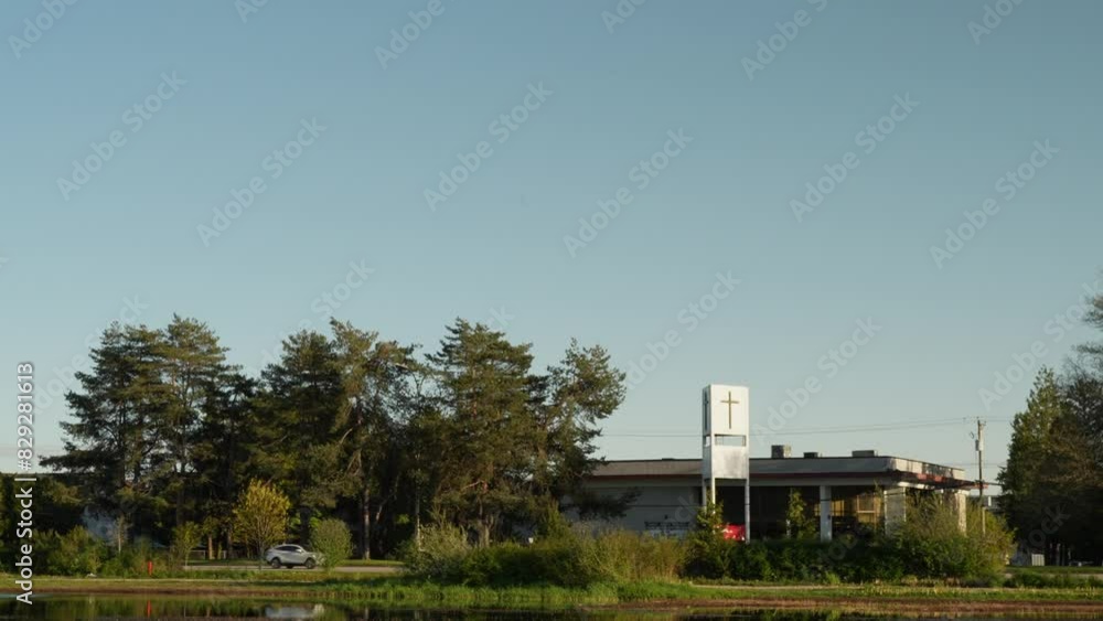 Church building with cross surrounded by trees and pond in a serene park Church building with cross surrounded by trees and pond in a serene park