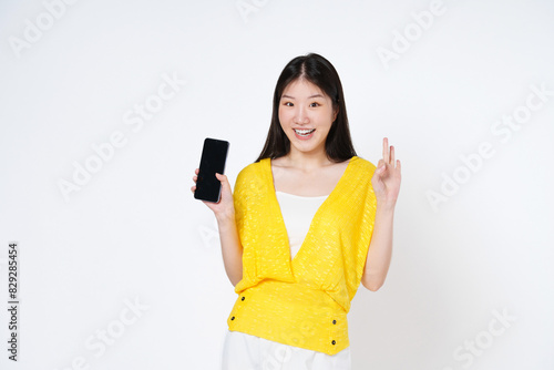 Asian woman, showing smartphone screen, app interface and ok sign, recommending application on mobile phone, standing over white background.