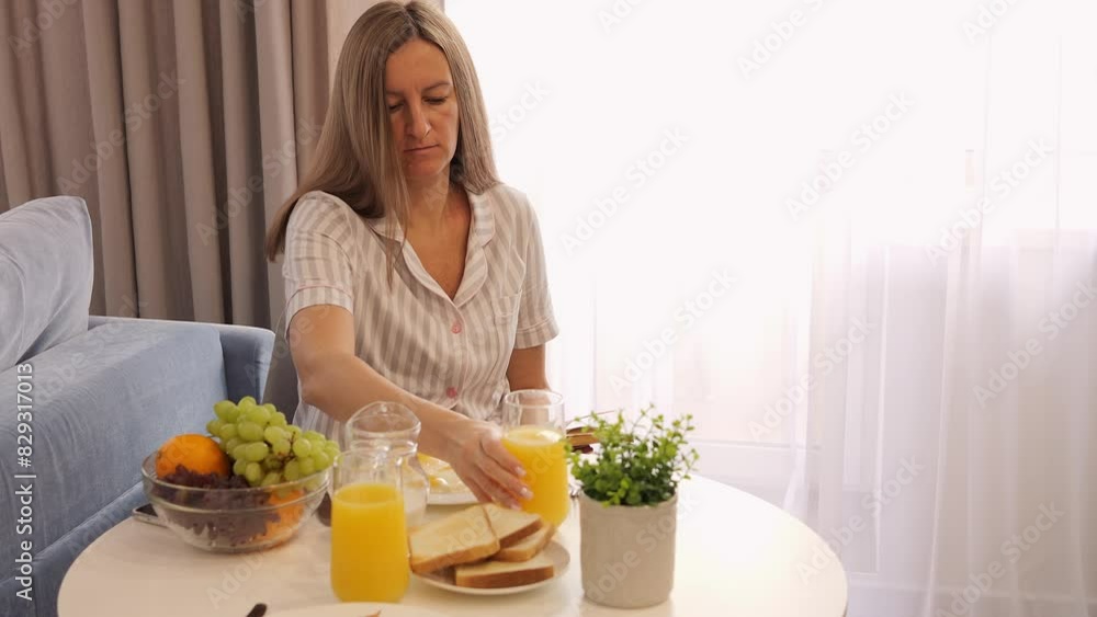 A woman enjoys breakfast, drinks juice and reads a book. Relaxing morning with juice, book and healthy lifestyle. Ideal for themes of calm and relaxation. Seize the moment with juice and a book. A woman enjoys breakfast, drinks juice and reads a book. Relaxing morning with juice, book and healthy lifestyle. Ideal for themes of calm and relaxation. Seize the moment with juice and a book.