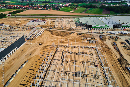 Obraz na płótnie Aerial view of construction site with warehouse building under construction for storage. Assembling industrial building with steel frame structure and roof truss. Infrastructure for logistics w salonie