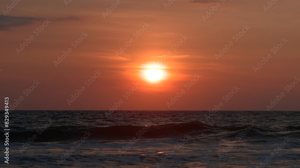 Beautiful rolling waves on background of setting sun. Action. Beautiful foaming waves move on background of bright sun at sunset. Orange sun over sea horizon with waves