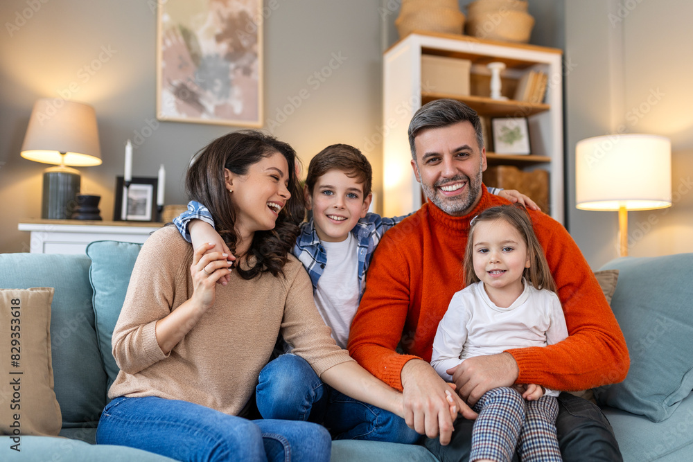 Happy family having fun at home, parents and little children sit on sofa together, Happy family sitting on sofa laughing together. Cheerful parents playing with their kids at home. Happy family having fun at home, parents and little children sit on sofa together, Happy family sitting on sofa laughing together. Cheerful parents playing with their kids at home.