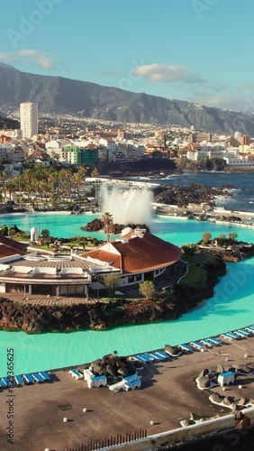 Aerial view of Puerto de la Cruz cityscape at sunrise, Tenerife, Spain. Purto de la Cruz town with Teide volcano at background on Tenerife, Canary islands. Swimming pool complex and waterfront photo