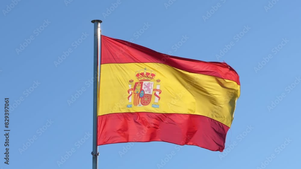Spanish flag waving in wind with blue sky. Spain banner blowing, soft and smooth silk. Cloth fabric texture ensign background. Use it for national day and country occasions concept. Spanish flag waving in wind with blue sky. Spain banner blowing, soft and smooth silk. Cloth fabric texture ensign background. Use it for national day and country occasions concept.