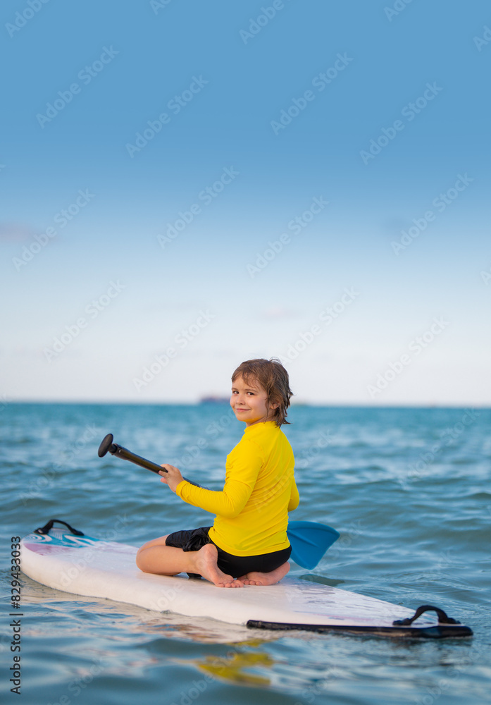 Summer vacation with kids in sea. Kid and Summer sea. Child boy paddling on paddle board or sup. Summer lifestyle. Summer Water sport. Kid Boy swimming with paddle board. Summer vacation with kids in sea. Kid and Summer sea. Child boy paddling on paddle board or sup. Summer lifestyle. Summer Water sport. Kid Boy swimming with paddle board.