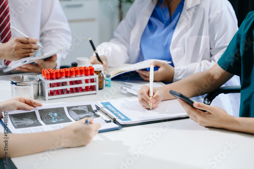 Medical team having a meeting with doctors in white lab coats and surgical scrubs seated