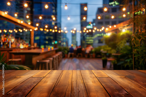 A wooden bar top in the foreground with a blurred background of an urban rooftop bar. The background includes stylish seating, plants, string lights, a panoramic city view.