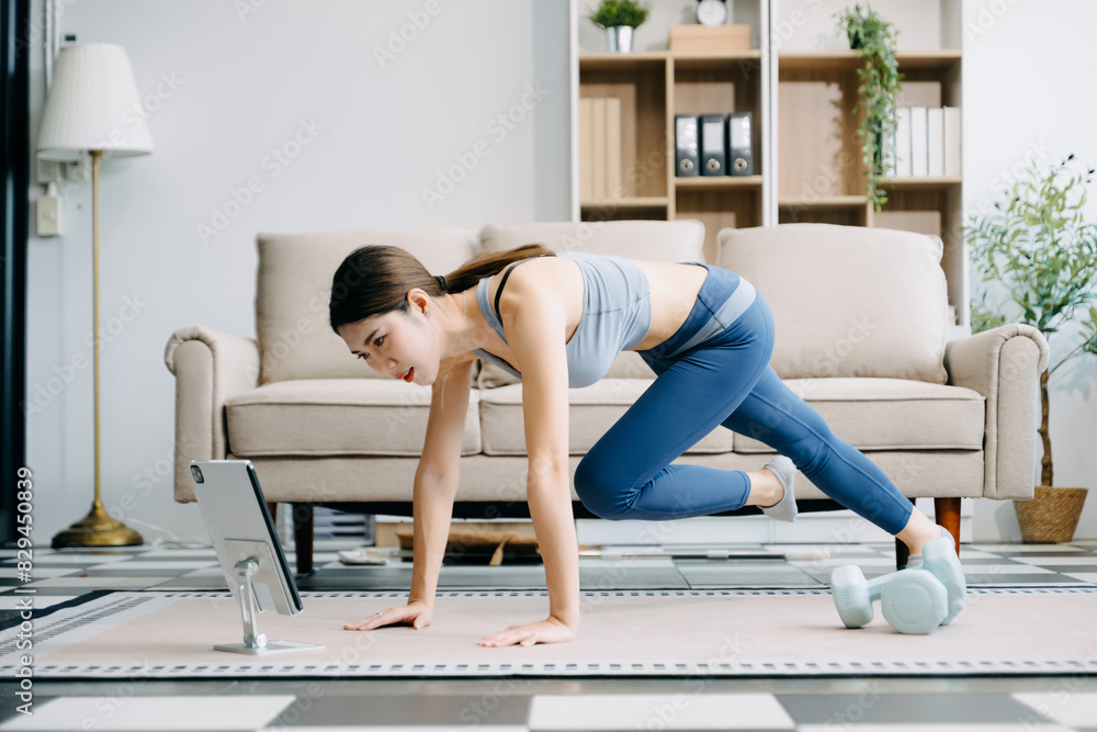 Asian Woman Doing Yoga and Watching Online Tutorials on Laptop, Training in Living Room at home Asian Woman Doing Yoga and Watching Online Tutorials on Laptop, Training in Living Room at home
